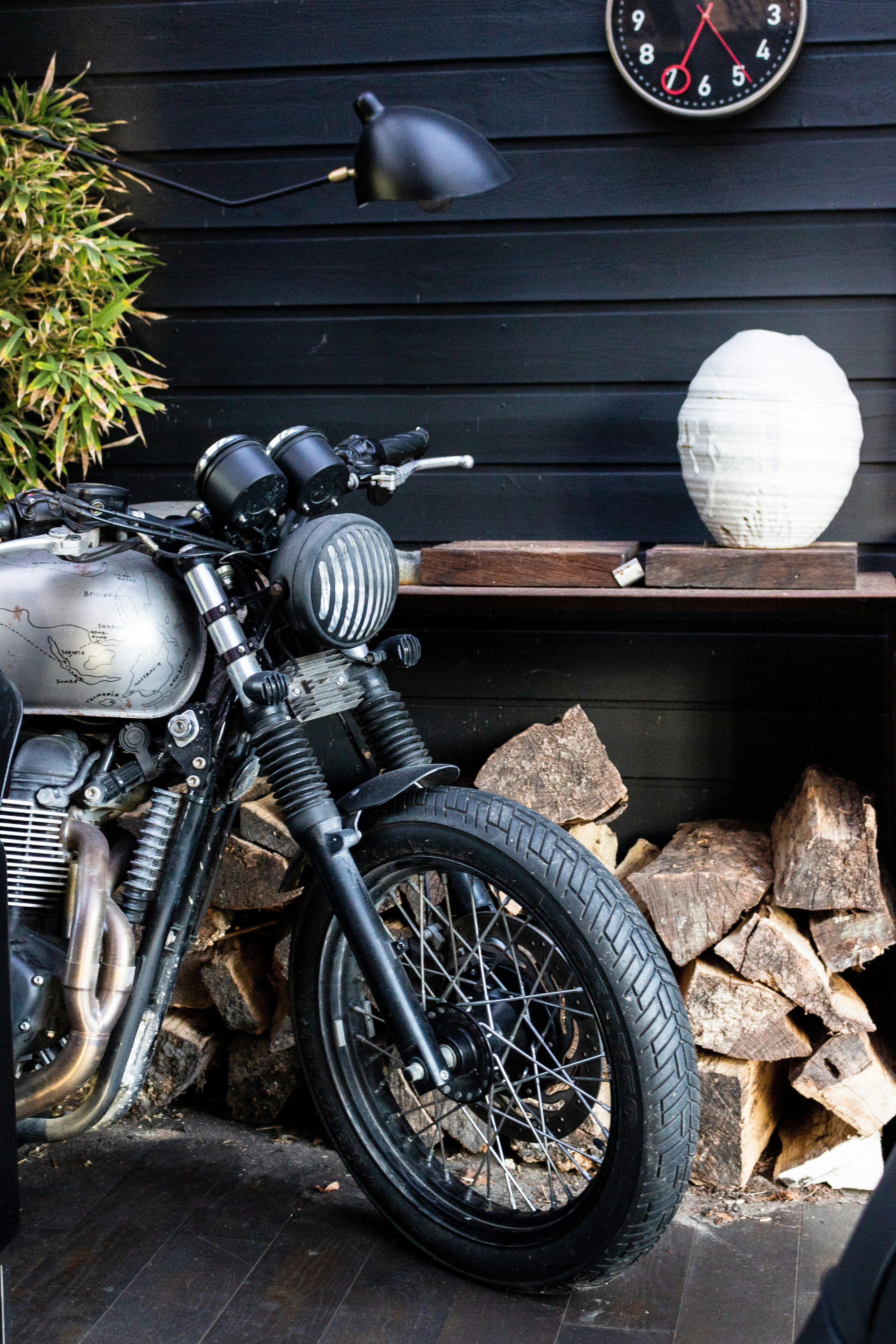 black motorcycle parked beside gray wooden wall